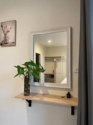 a mirror on a wall with a vase on a shelf at Sunny Balcony in Ban Khlong Haeng