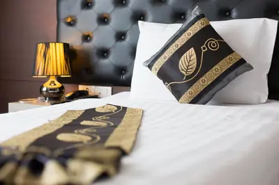 a bed with a black and gold blanket and a pillow at Hemingways Silk Hotel in Patong Beach