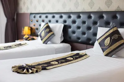 two beds in a hotel room with a blanket on them at Hemingways Silk Hotel in Patong Beach
