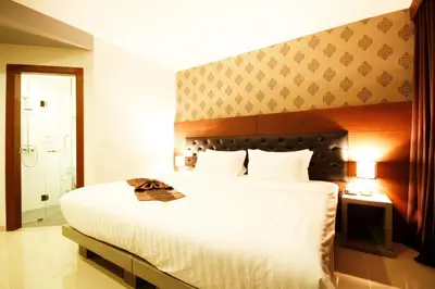 a bedroom with a large white bed with a headboard at Hemingways Silk Hotel in Patong Beach