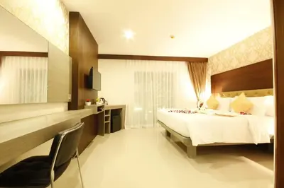 a bedroom with a bed and a desk and a chair at Hemingways Silk Hotel in Patong Beach