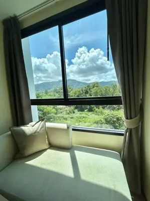 a couch in front of a window with a view at 1 Large Bedroom in Prime Bangtao in Bang Tao Beach
