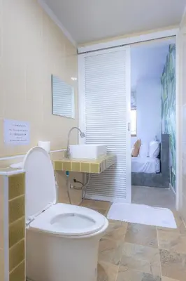 a bathroom with a toilet and a sink and a bed at Sunrise Serenity Phuket Resort in Karon Beach