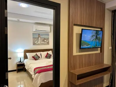 a bedroom with a bed and a tv on a wall at Nai Harn Condominium in Rawai Beach