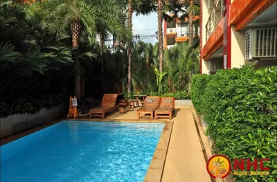a swimming pool with benches and chairs next to a building at Nai Harn Condominium in Rawai Beach