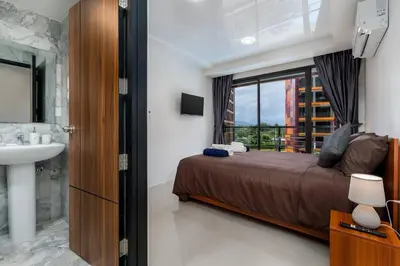 a bedroom with a bed and a sink and a window at 1 BR apartment 777 Beach Condotel in Mai Khao Beach