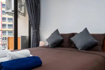 a bedroom with a brown bed with blue and white pillows at 1 BR apartment 777 Beach Condotel in Mai Khao Beach