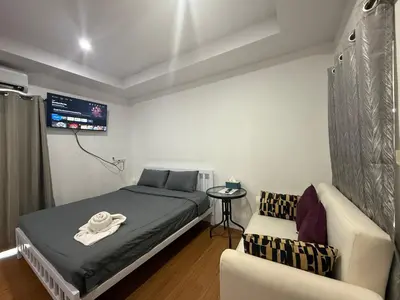 a bedroom with a bed and a chair and a tv at Bangtao Corner in Bang Tao Beach