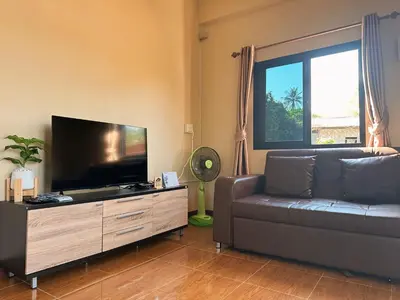 a living room with a couch and a flat screen tv at บ้านสวยกานต์ชนิต in Ko Yao Noi