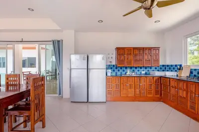 a kitchen with a white refrigerator and wooden cabinets at Kamala Heights Villa in Kamala Beach