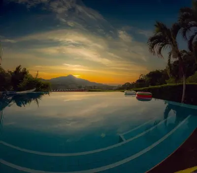 a large swimming pool with a sunset in the background at Kamala Heights Villa in Kamala Beach