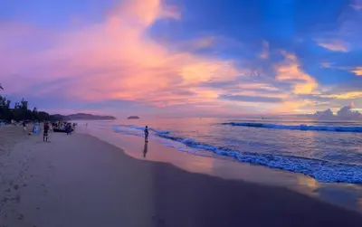 a group of people walking on the beach at sunset at Bestin Karon 1 - Apartment GF- 1 min from Karon beach in Karon Beach