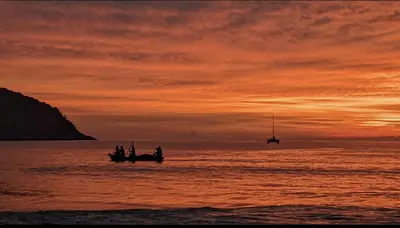 a group of people in boats in the ocean at sunset at Charming Beachside Studio in Rawai Beach