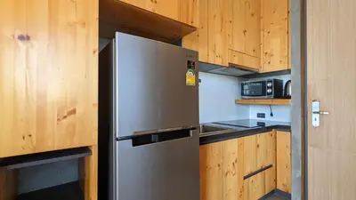 a stainless steel refrigerator in a kitchen with wooden cabinets at Charming Beachside Studio in Rawai Beach