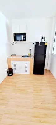 a kitchen with a black refrigerator and a wooden floor at The pink palace in Karon Beach