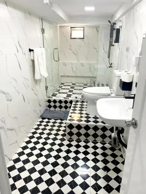 a bathroom with two toilets and a black and white checkered floor at The pink palace in Karon Beach