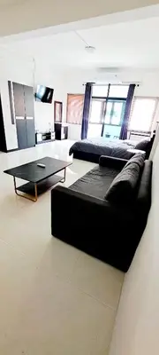 a living room with a black couch and a table at The pink palace in Karon Beach