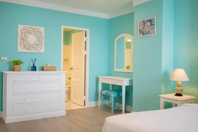 a bedroom with blue walls and a bed and a desk at Waterfront High Tide Suite - Ocean View in Karon Beach