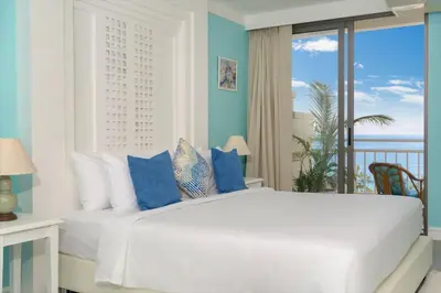 a bedroom with a large white bed with blue accents at Waterfront High Tide Suite - Ocean View in Karon Beach