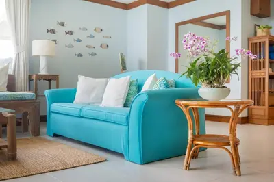 a blue couch in a living room with a table at Waterfront High Tide Suite - Ocean View in Karon Beach