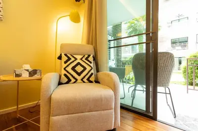 a living room with a chair and a balcony at Neatest Apartment 50m To Main Street And Beach C149 in Rawai Beach