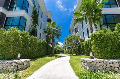 a walkway in front of a building with palm trees at Neatest Apartment 50m To Main Street And Beach C149 in Rawai Beach
