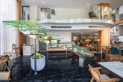 a glass staircase in a restaurant with tables and chairs at The Blue Mavi Hotel in Chalong