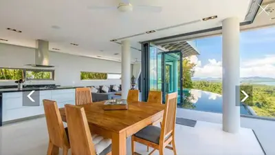 a kitchen and dining room with a wooden table at Ocean Heart 5BDR Seaview LUX villa in Ban Bang La