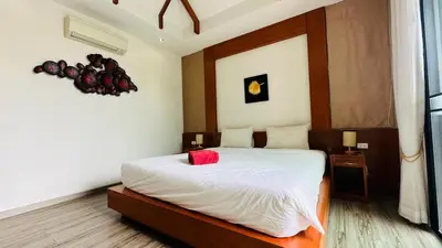 a bedroom with a bed with a red pillow on it at Rawaii Vip Villa 2D101 in Phuket Town