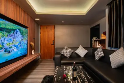 a living room with a couch and a large screen tv at Three Double U - Kalim Sea View in Patong Beach