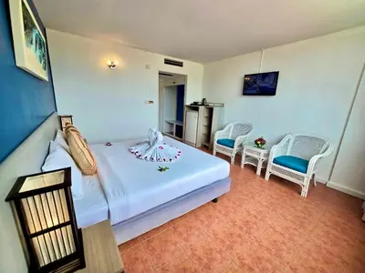 a bedroom with a white bed and two chairs at ON Hotel Phuket - SHA in Karon Beach