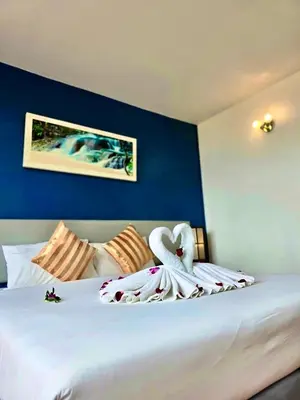 a bedroom with a large white bed with a blue wall at ON Hotel Phuket - SHA in Karon Beach