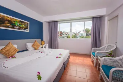 a hotel room with two beds and a window at ON Hotel Phuket - SHA in Karon Beach