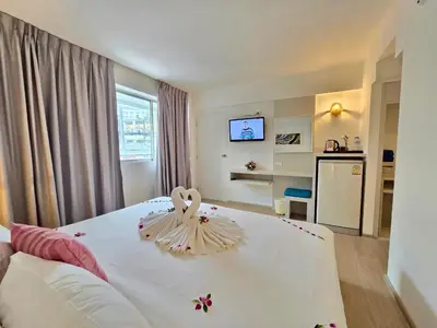 a bedroom with a white bed with flowers on it at ON Hotel Phuket - SHA in Karon Beach