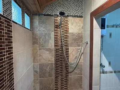 a shower in a bathroom with a brick wall at Cozy Garden Cottage in Ao Nang