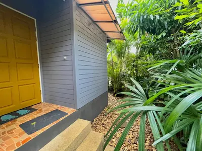 a house with a yellow door and some plants at Cozy Garden Cottage in Ao Nang