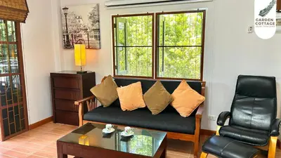 a living room with a couch and a table at Cozy Garden Cottage in Ao Nang