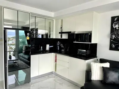 a kitchen with white cabinets and a living room at Kata Ocean View 1 bedroom 50 m2 in Kata Beach
