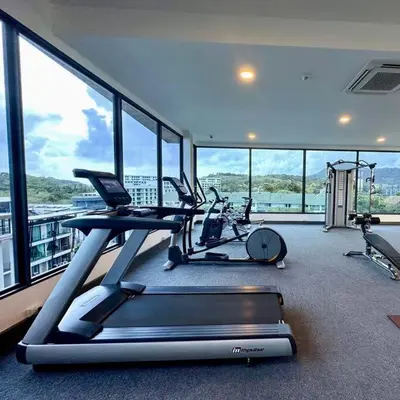 a gym with two exercise bikes in a room with windows at One bedroom apartment Calypso Garden in Phuket Town