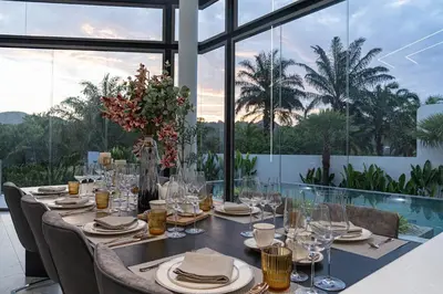 a dining room with a long table with chairs and glasses at Luxury Golfside Villa near Patong - Villa Priva in Kathu