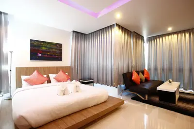 a bedroom with a large white bed and a chair at Buasri By Ohm in Patong Beach