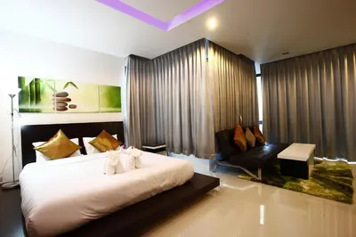 a bedroom with a large white bed and a chair at Buasri By Ohm in Patong Beach