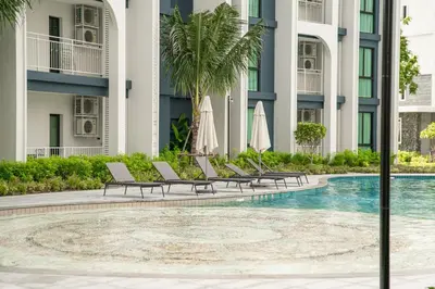 a pool with chairs and umbrellas in front of a building at Title Halo Andaman Coast Pool View Gym in Nai Yang Beach