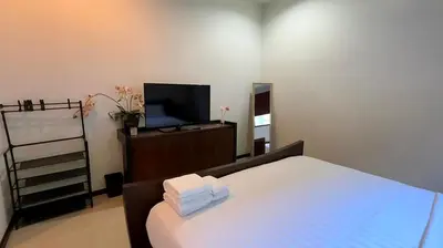 a bedroom with a bed with a television and towels at Onyx Pool Villa in Phuket Town