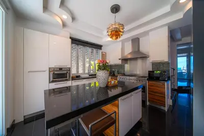 a kitchen with white cabinets and a black counter top at \u542b\u65e9\u9910\u9001\u63a5\u673a Phuket patong 4Bedrooms seaview Pool villa in Patong Beach