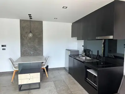 a kitchen with black cabinets and a table and chairs at Modern apartment on Naiharn Beach B404 in Rawai Beach