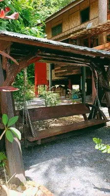 a wooden bench in front of a building at Bangtao Wooden house resort and cafe in Ban Thalat Choeng Thale