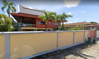 a house with a yellow wall and palm trees at 2,5 Zimmerwohnung mit Pool und Pavillon in Rawai Beach