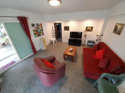 a living room with a red couch and a table at 2,5 Zimmerwohnung mit Pool und Pavillon in Rawai Beach