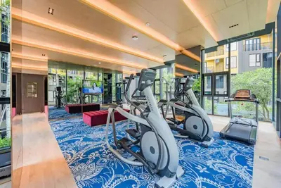 a gym with treadmills and ellipticals on a blue carpet at The Base Central Phuket in Phuket Town